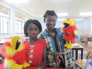 Two children hold the puppet parrots ZuZu and ZaZa