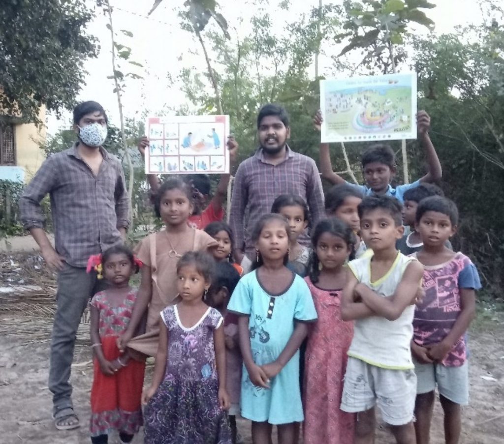 A photo of two teachers and a group of children - one of the children is holding a copy of a malaria poster and another is holding the Children for Health Vision poster.