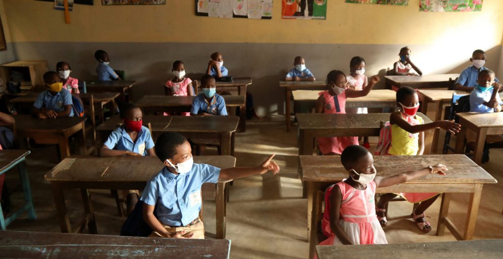 Children in school sit 2 meters apart while wearing masks during the COVID-19 pandemic.